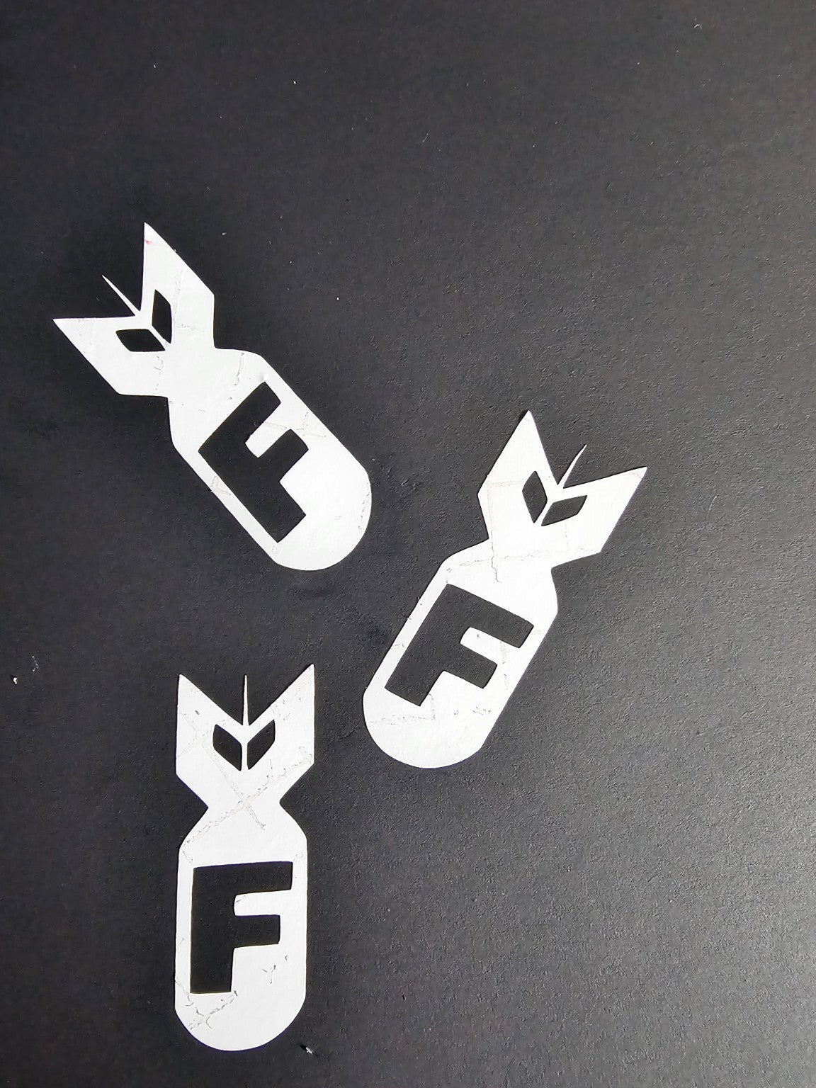 Three white F-bomb vinyl decals displayed on a black background